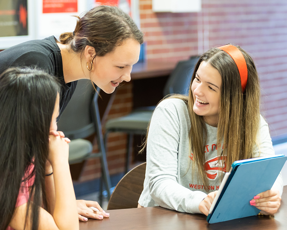 Two WKU Students smile while looking at an iPad.