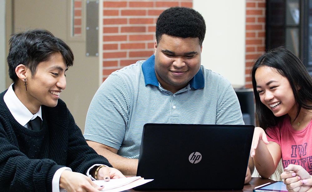 Three WKU students sit together to work on a project at a table in Grise Hall.