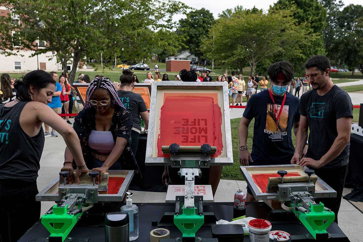 Students participating in a community event screen printing shirts.