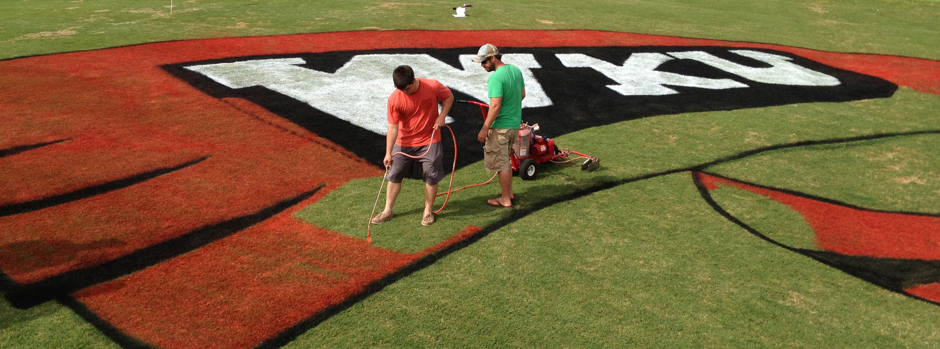 Students painting Red Towel on Turf