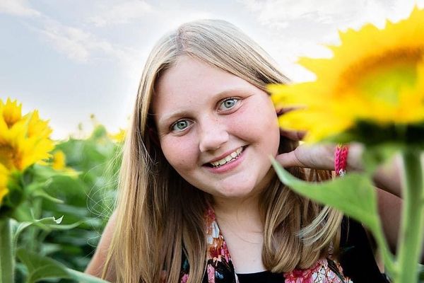 young girl in front of sunflowers
