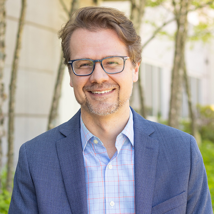Man in blue blazer with glasses and blonde hair