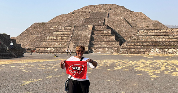 Image of a woman holding a Red Towel in front of a Mexican pyramid
