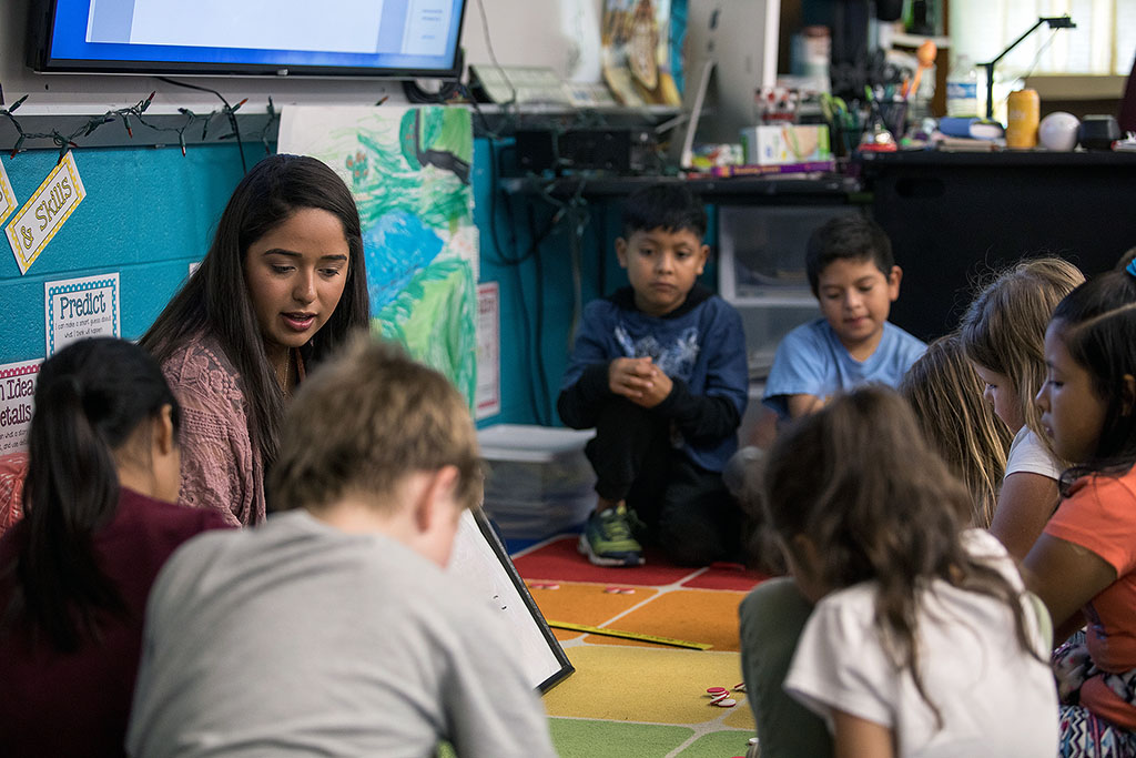 Student teacher in a classroom reading to young students