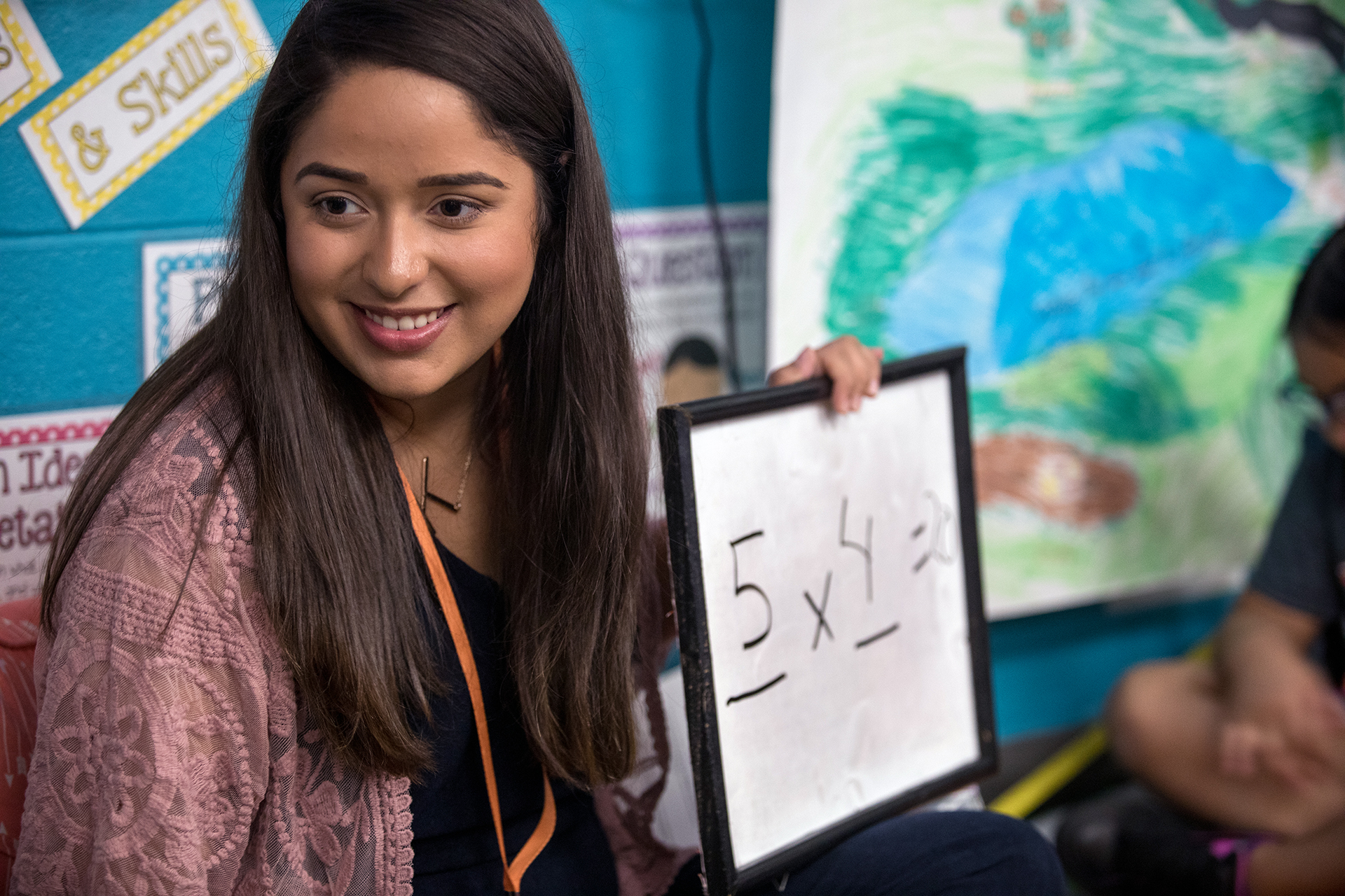 Image of student holding a white board in a classroom.