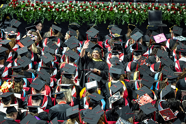 Graduate waving at family members in the arena