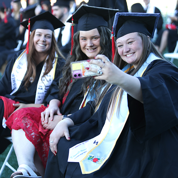 WKU Graduates posing for a selfie while holding a cell phone