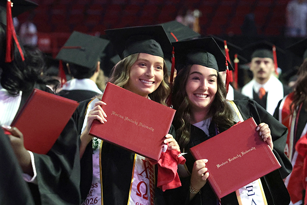 WKU graduates taking a photo with diploma covers