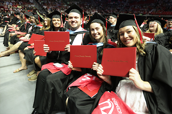 WKU Graduates holding their diploma covers while smiling