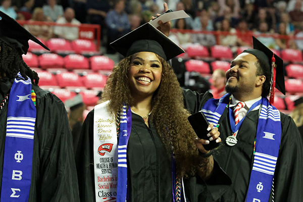 WKU graduates smiling and waving at the crowd