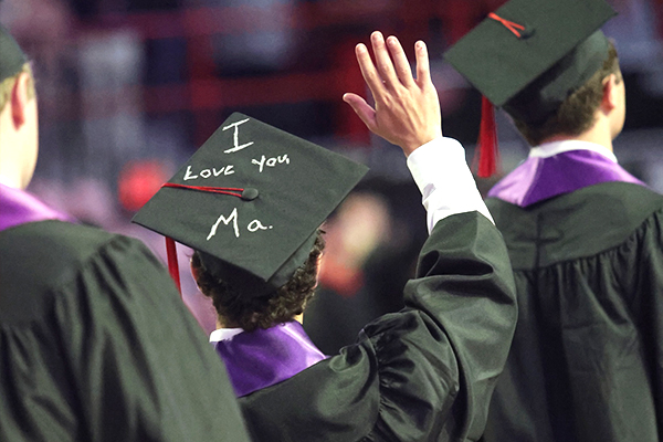 WKU graduate waving and showing a cap saying I love you Ma