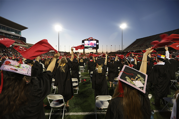 Graduates waving red towels on Feix Field during Commencement
