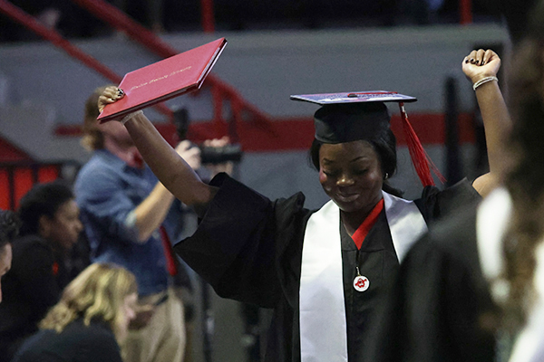 Graduate holding up a diploma cover and hands in celebration