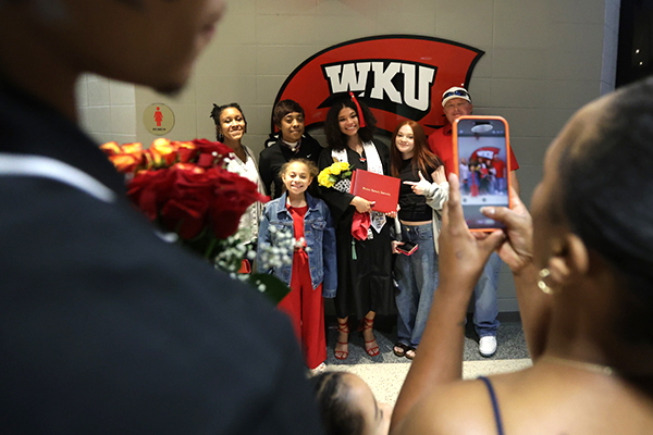 A family poses for a picture with a graduate in Diddle Arena