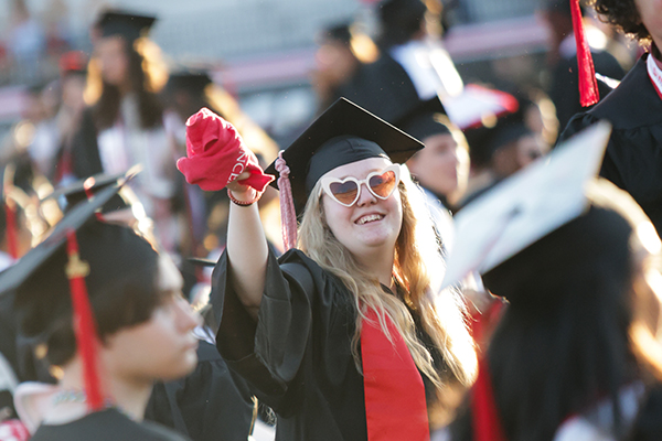 graduate with heart sunglasses waving red towel during topper walk