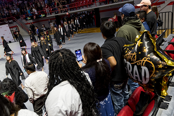 families watching and taking photos of graduate procession