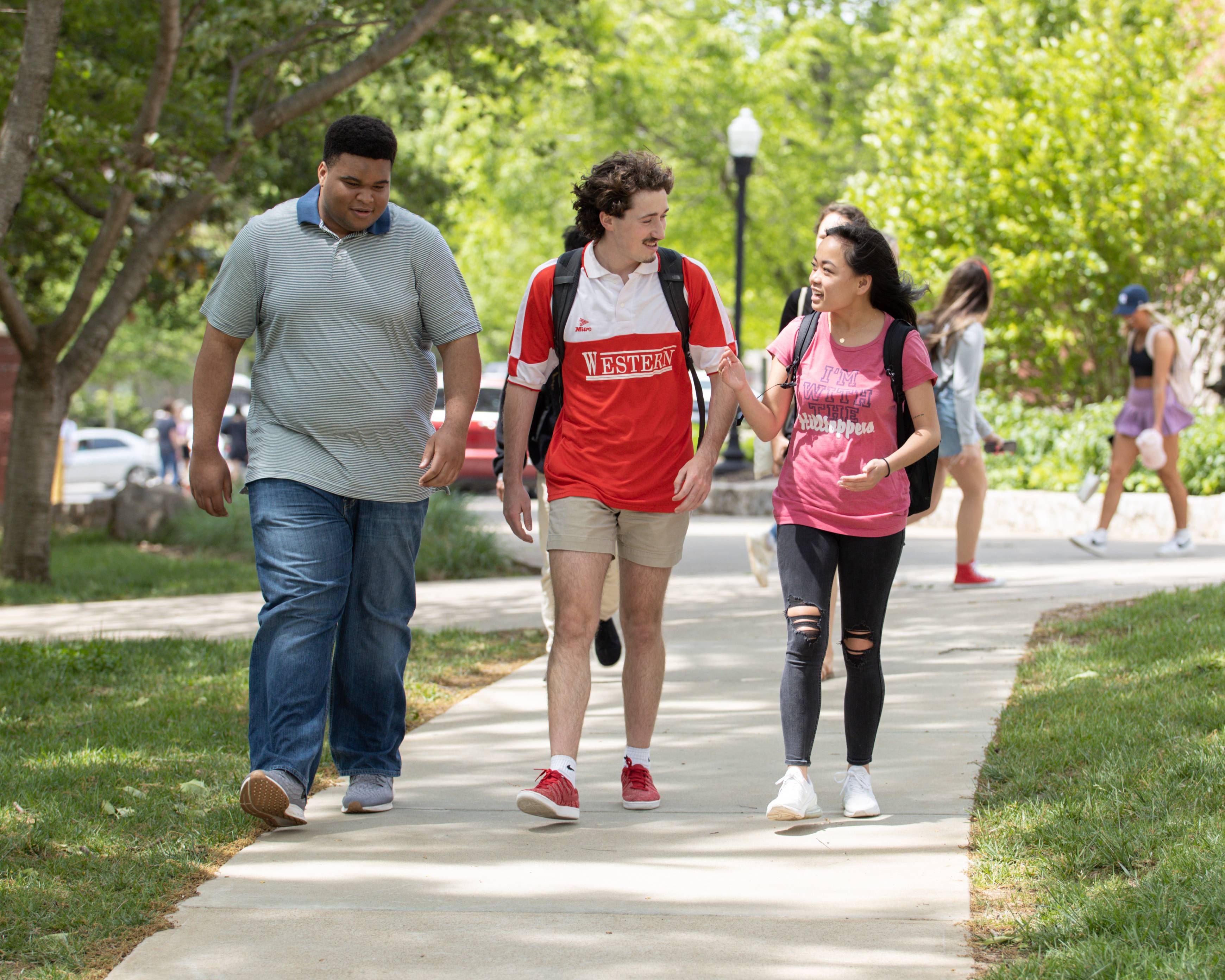 Three WKU students walk and talk in front of Grise Hall.