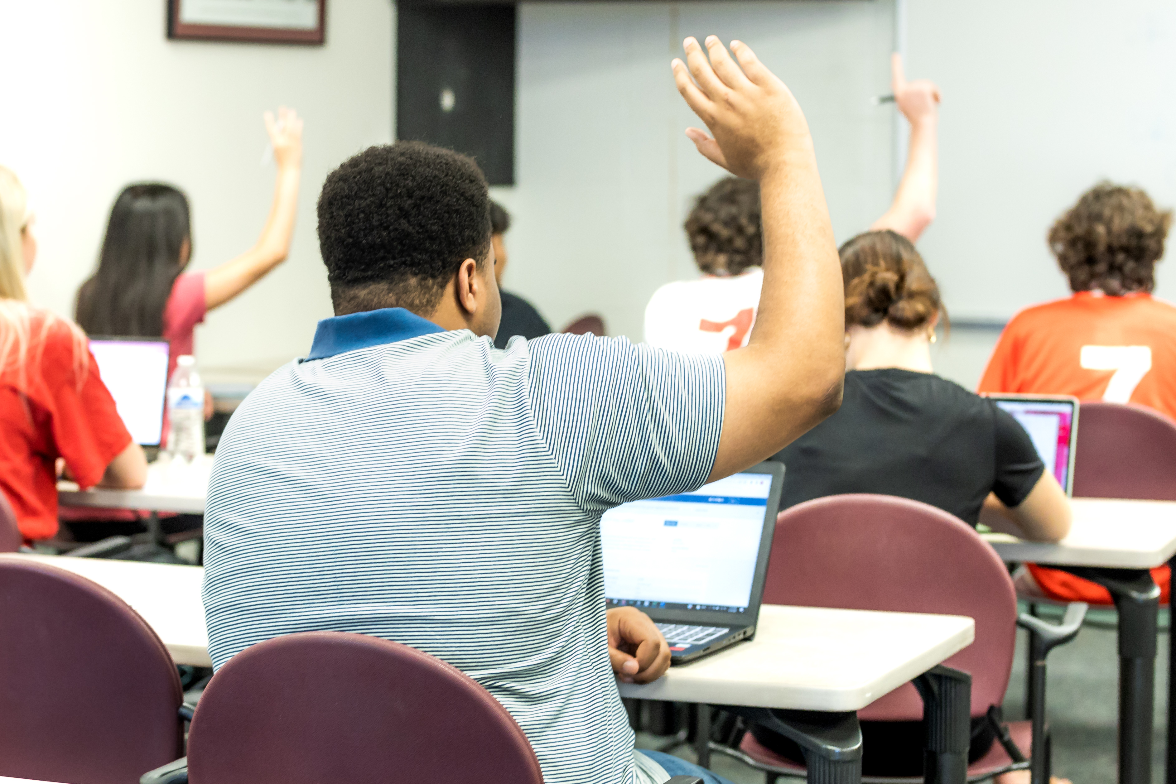 Student raising hand in class.