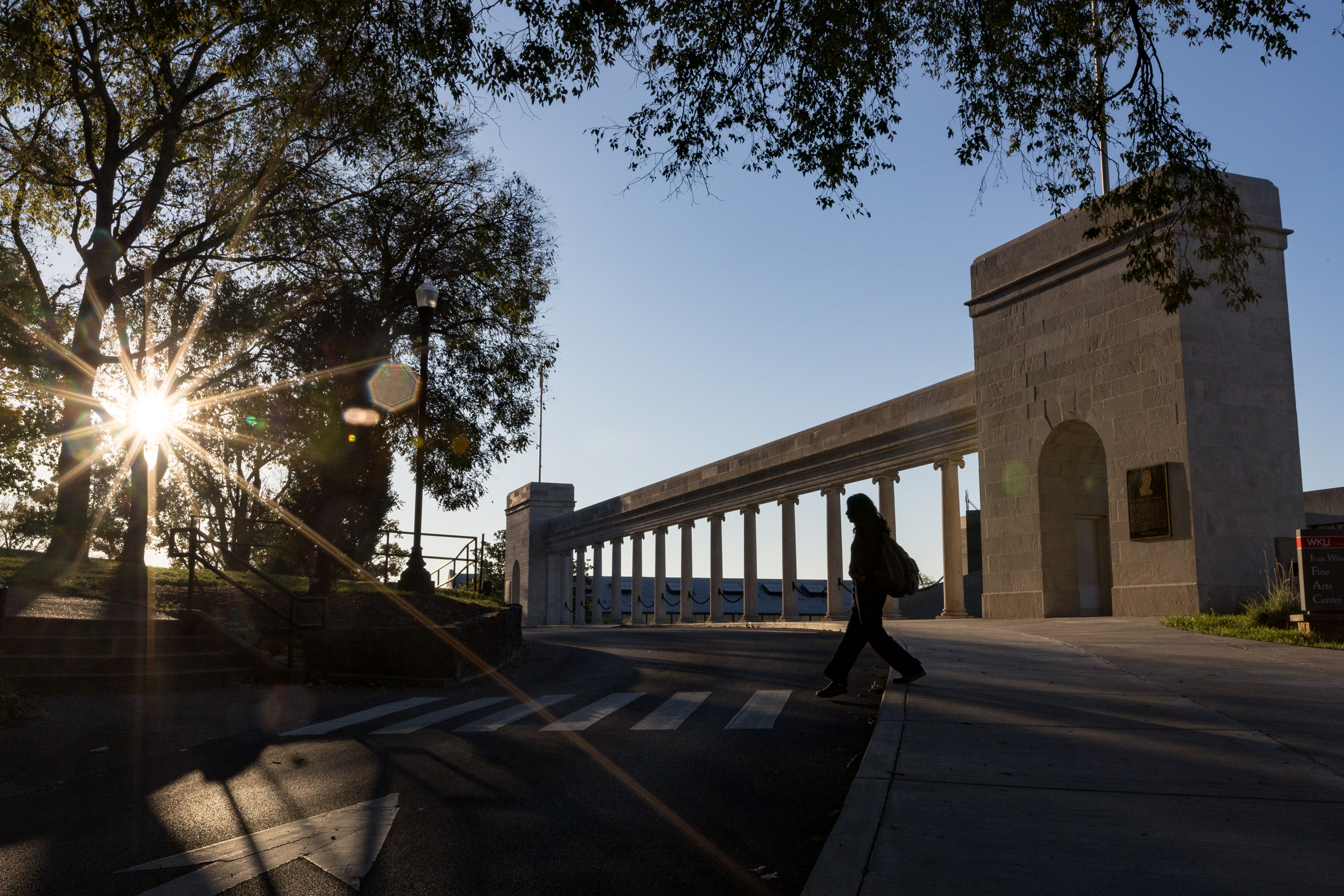 Student walking in front of the Western Kentucky University Colonnades.