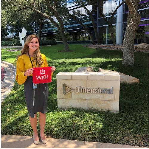 WKU student stands holding a WKU red towel with the Dimensional company sign to her right.