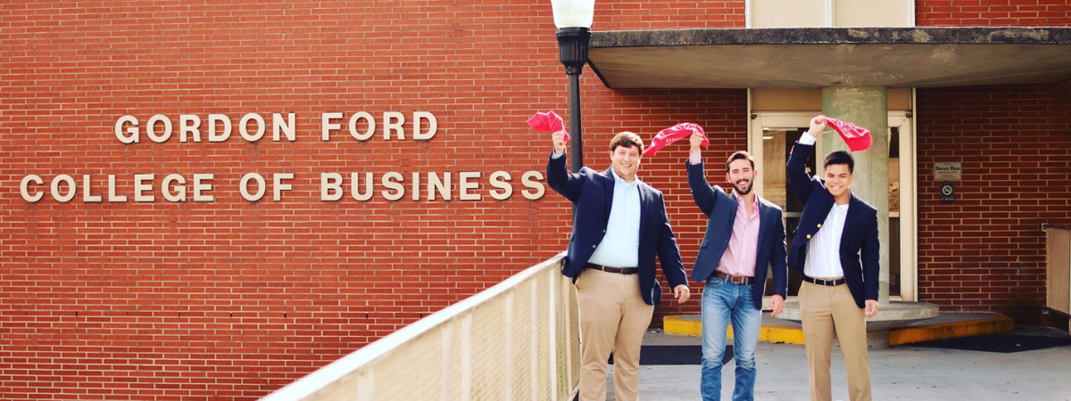 Three students wave red towels outside of Grise Hall.