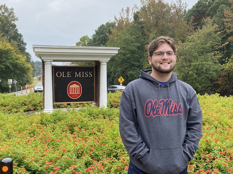 Jack stands in front of an Ole Miss sign wearing an Ole Miss sweatshirt