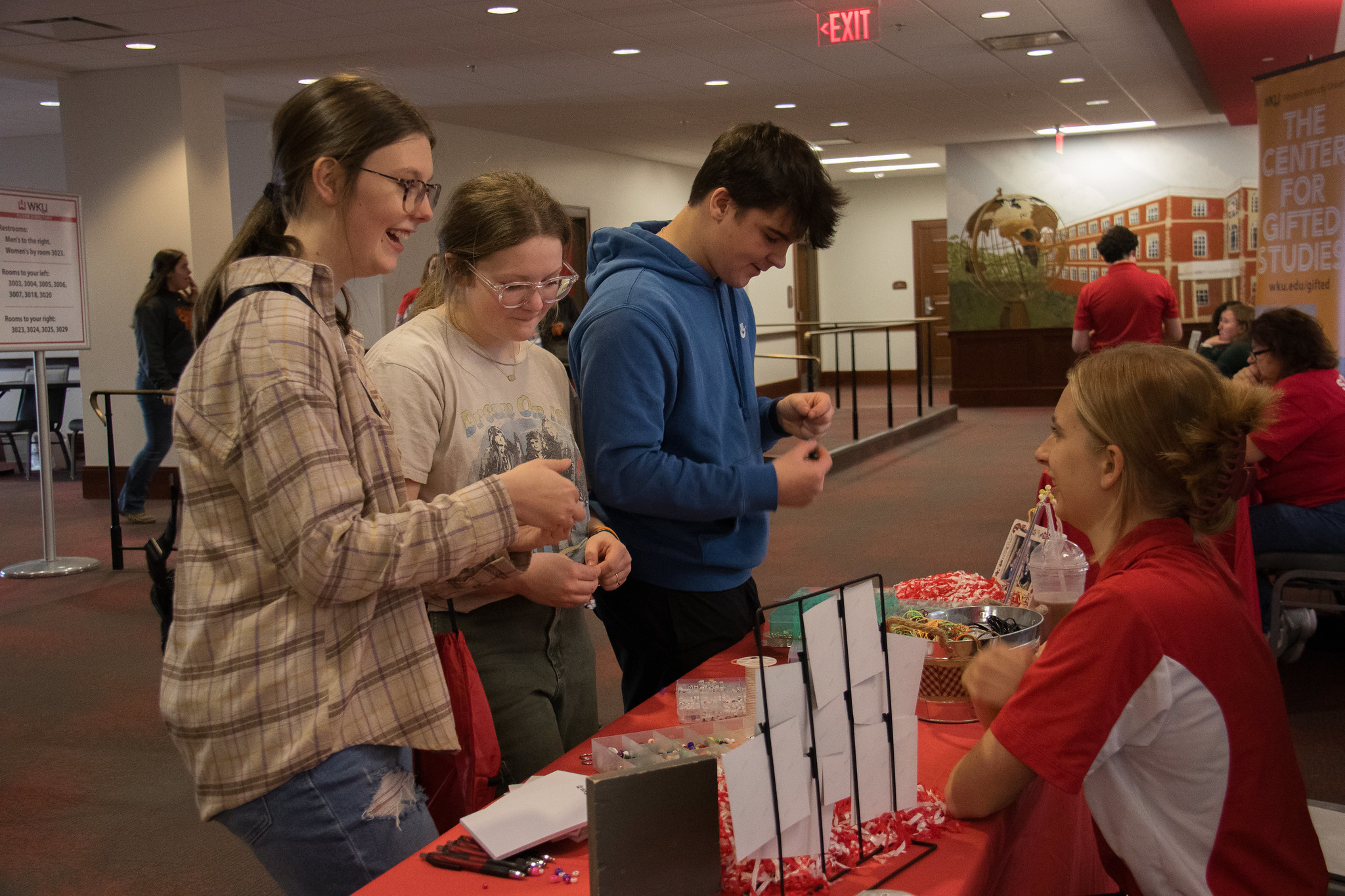 three young people smiling at adult sitting at a table. 