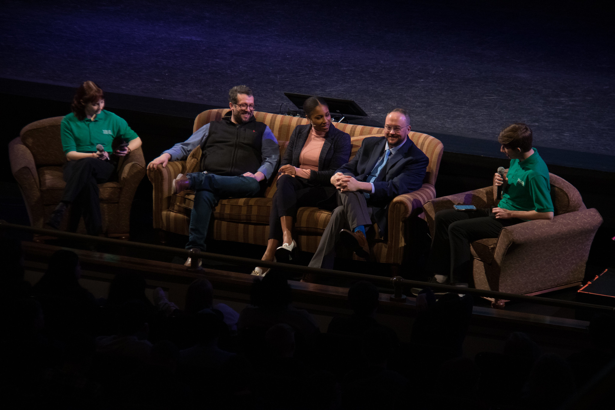 group of men and women sitting on couch facing an audience