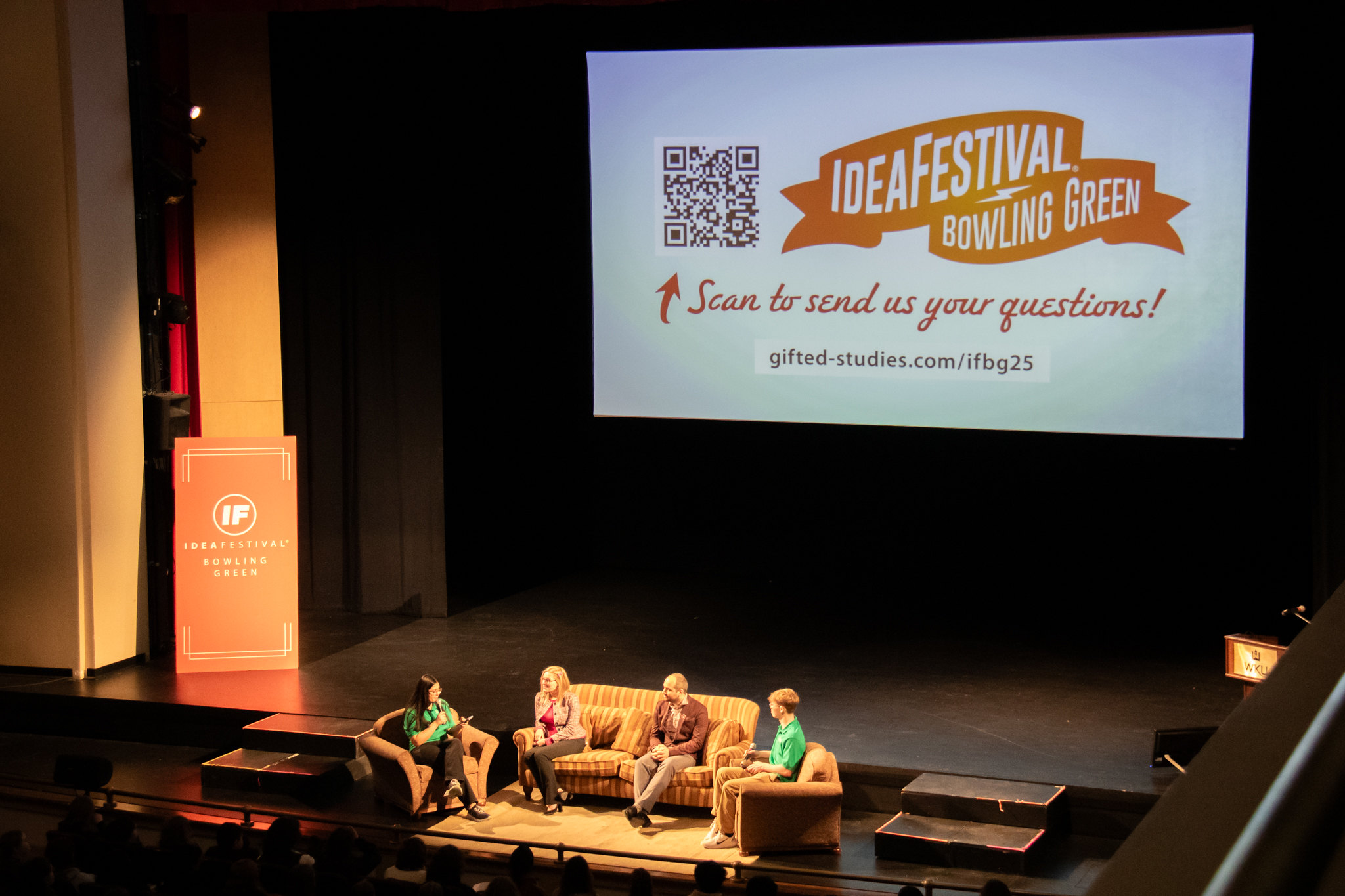 group of adults sitting on a couch on a stage facing an audience