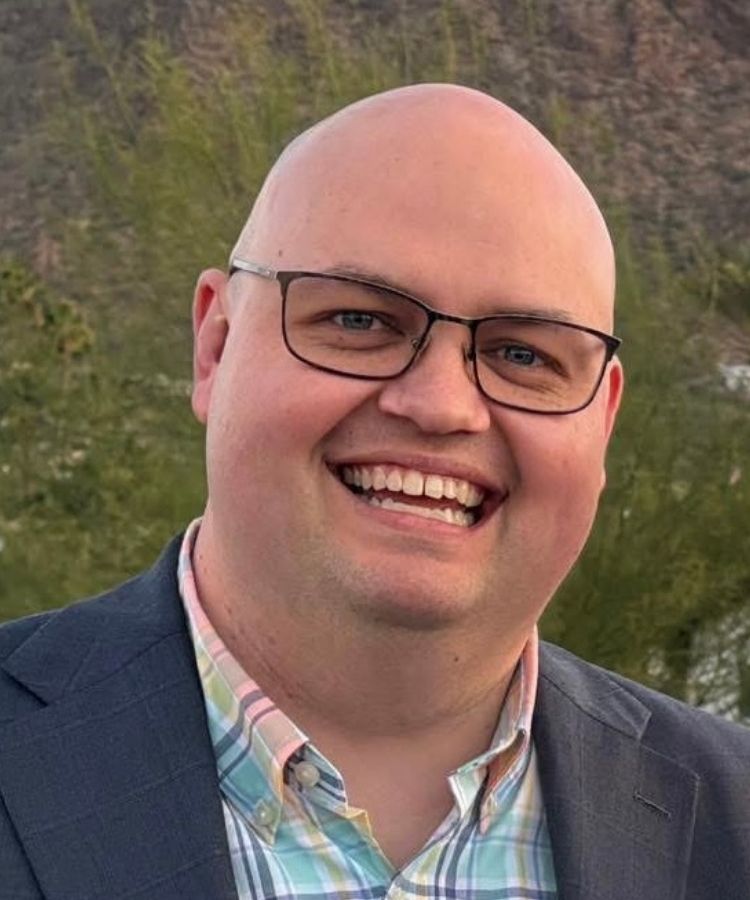 man in a dark blazer smiling at the camera