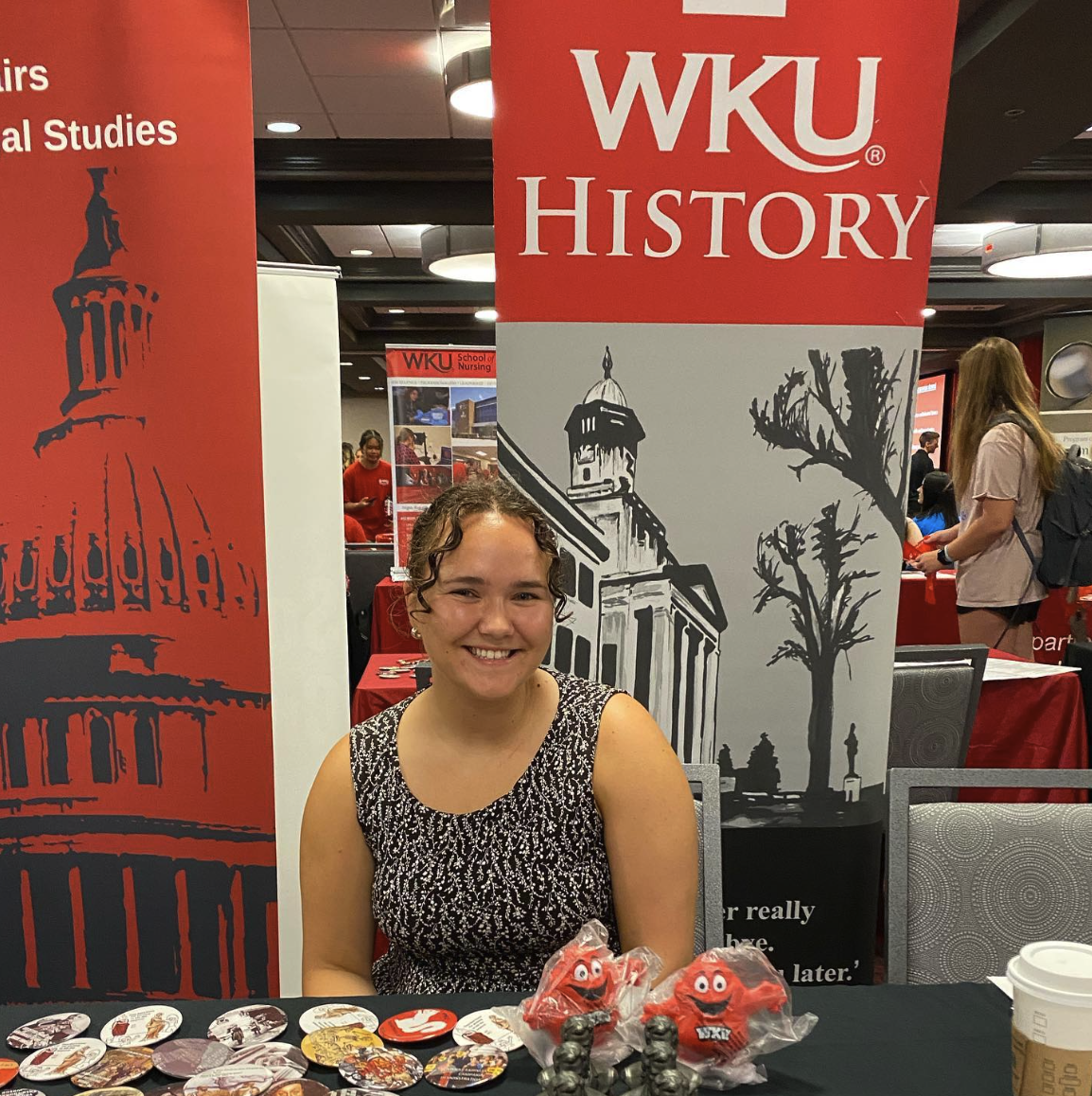 Woman smiling at a table recruitment event.