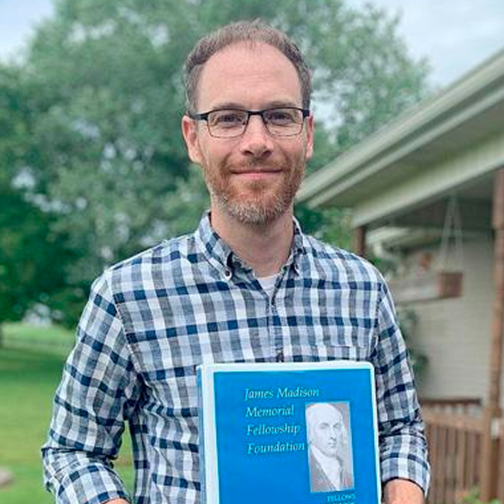 Mike Jones smiling holding a book