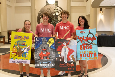 A distance picture of a group of students holding directions painted signs.
