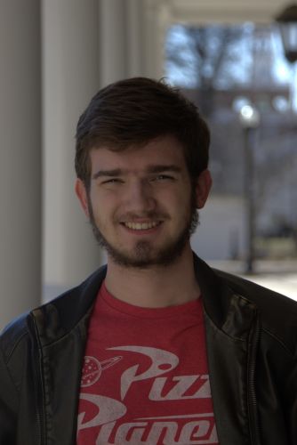young caucasian man with brown hair in a casual tshirt smiling at camera