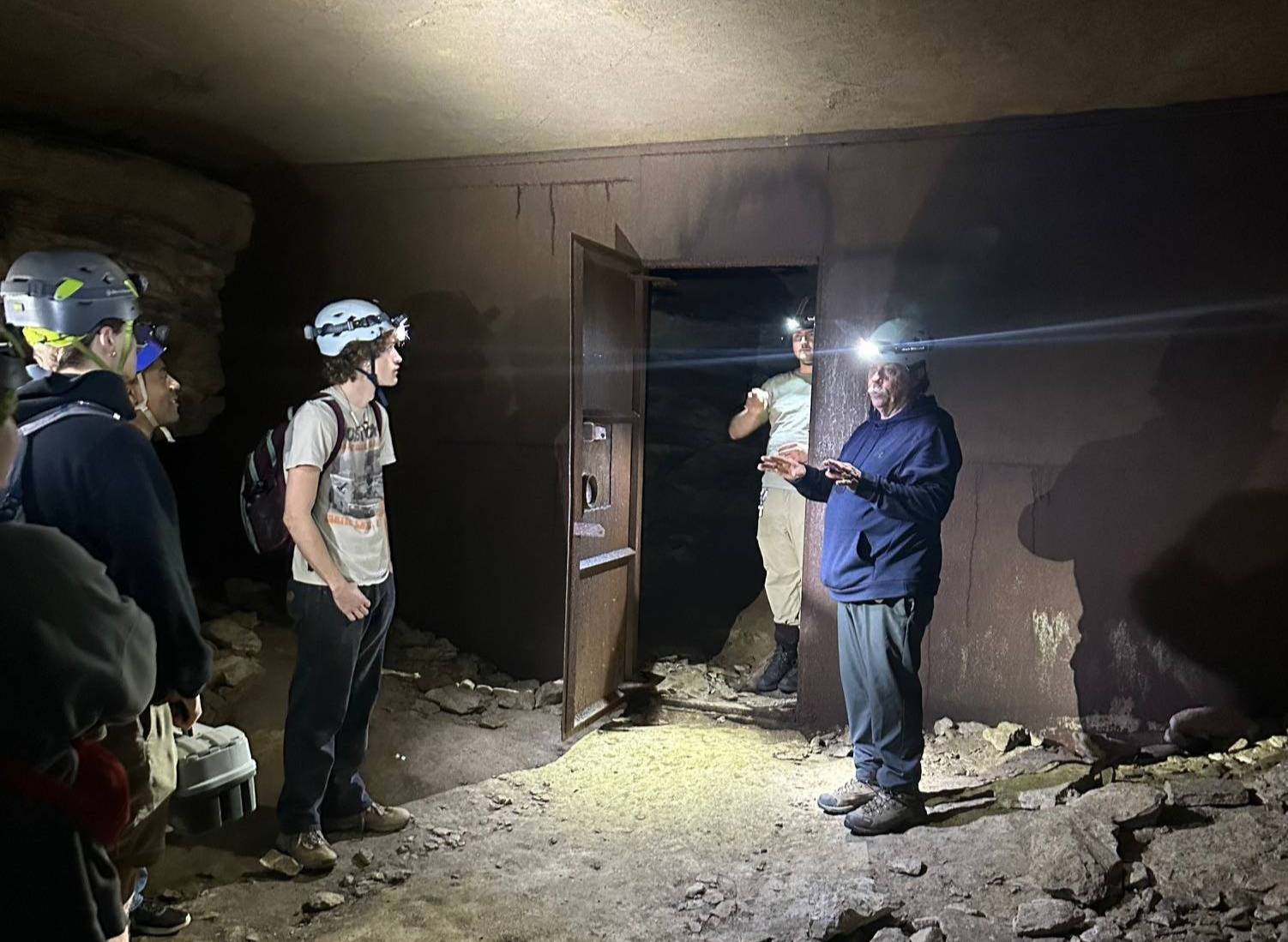 group of students and faculty wearing helmets inside Mammoth Cave