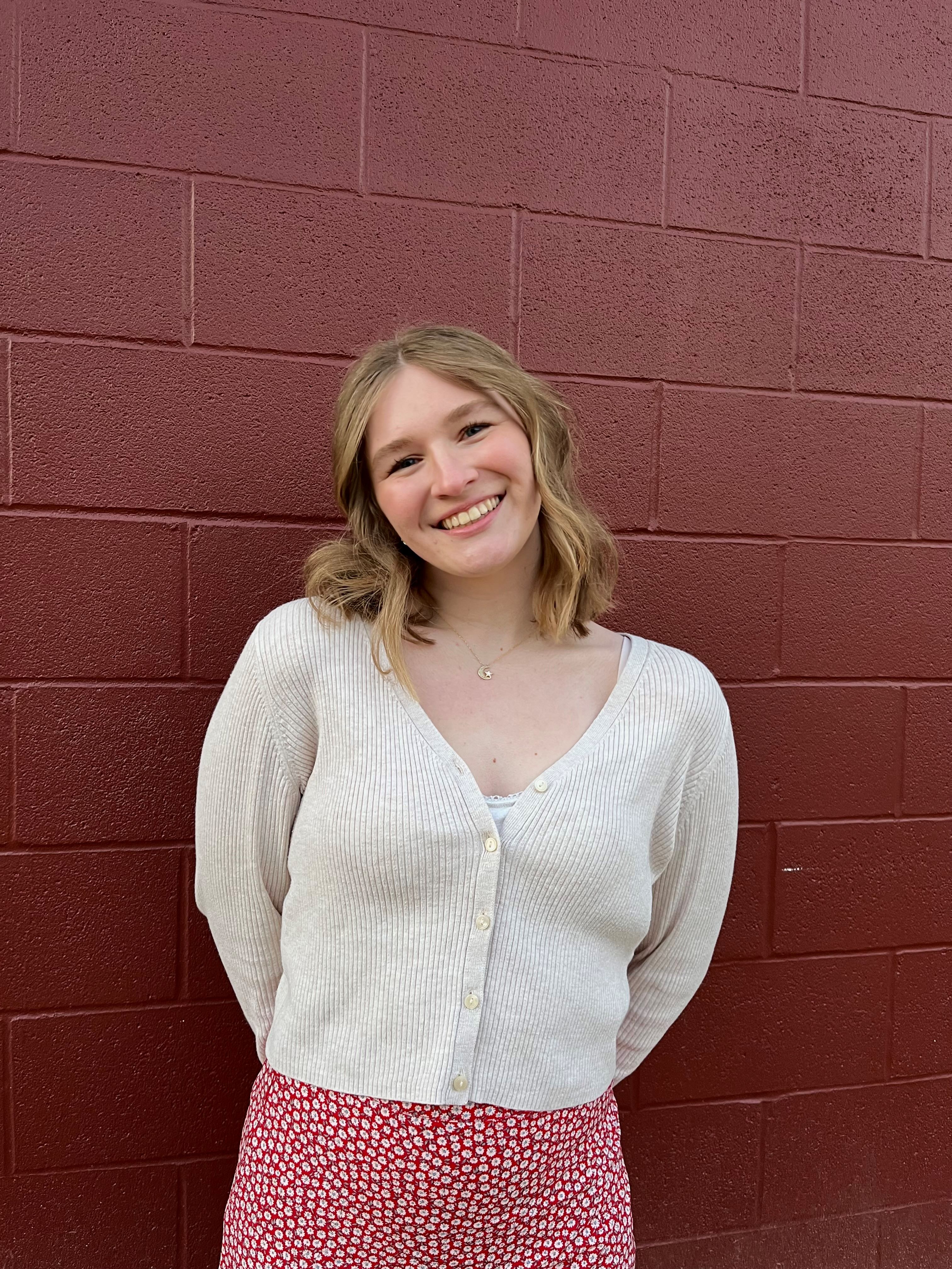 Blonde student smiling in front of a red barn