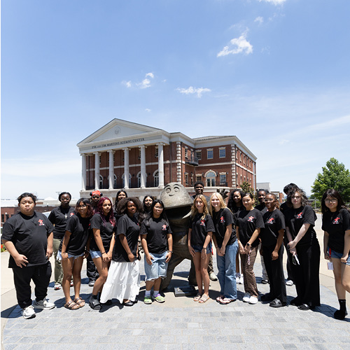 This photo feature the group of first gen high school students gathered around the Big Red statue in front of the Alumni Center.