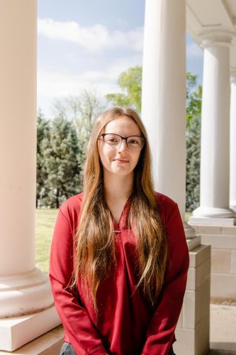 young woman smiling in front of a column outdoors