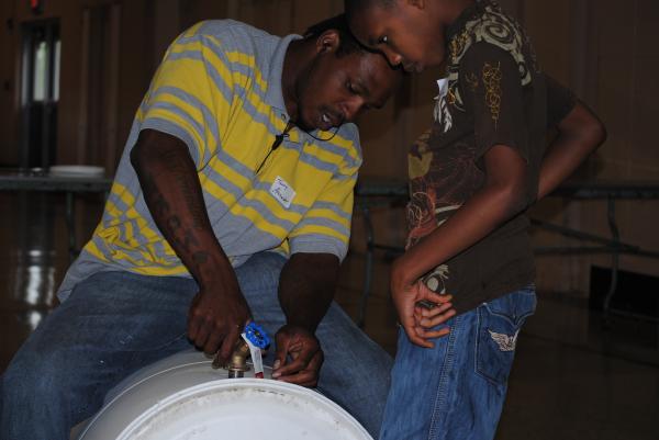 Father helps insert spigot into the hole.