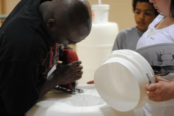 Parent cuts the hole out of the barrel to insert bucket.