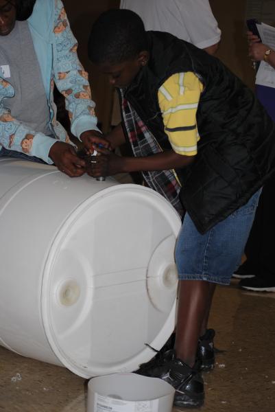 Child helps insert spigot into the barrel.