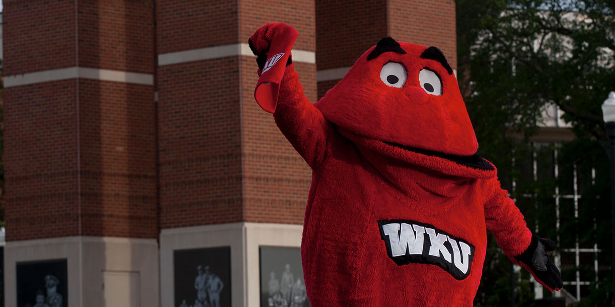 Big Red holding a red towel in front of the Guthrie Bell Tower