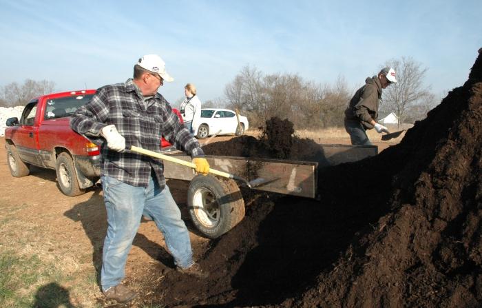 volunteers shoveling mulch into trailer