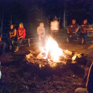 View Participants sitting around a bonfire Larger