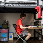 Male student working on a laptop under the lofted bed in Regents Hall