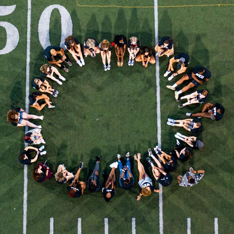 Aerial photos of MASTER Plan mentors sitting in a circle on the football field