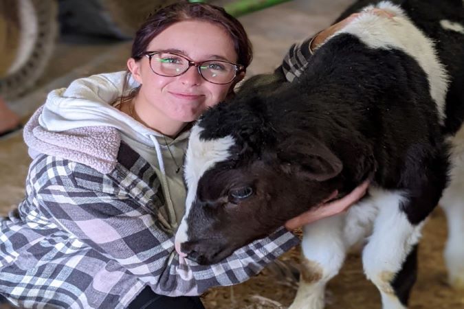 Student posing with a calf.