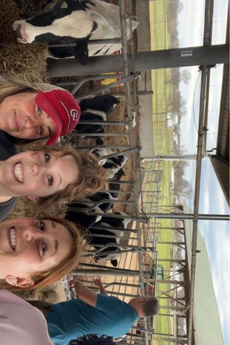 HMD students and faculty taking a selfie in front of some cows at a farm.