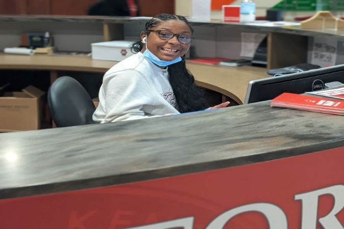 Student sitting at the information desk smiling at the camera.