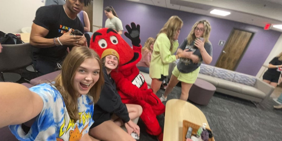 Resident Assistant and residents with Big Red in a pod lounge